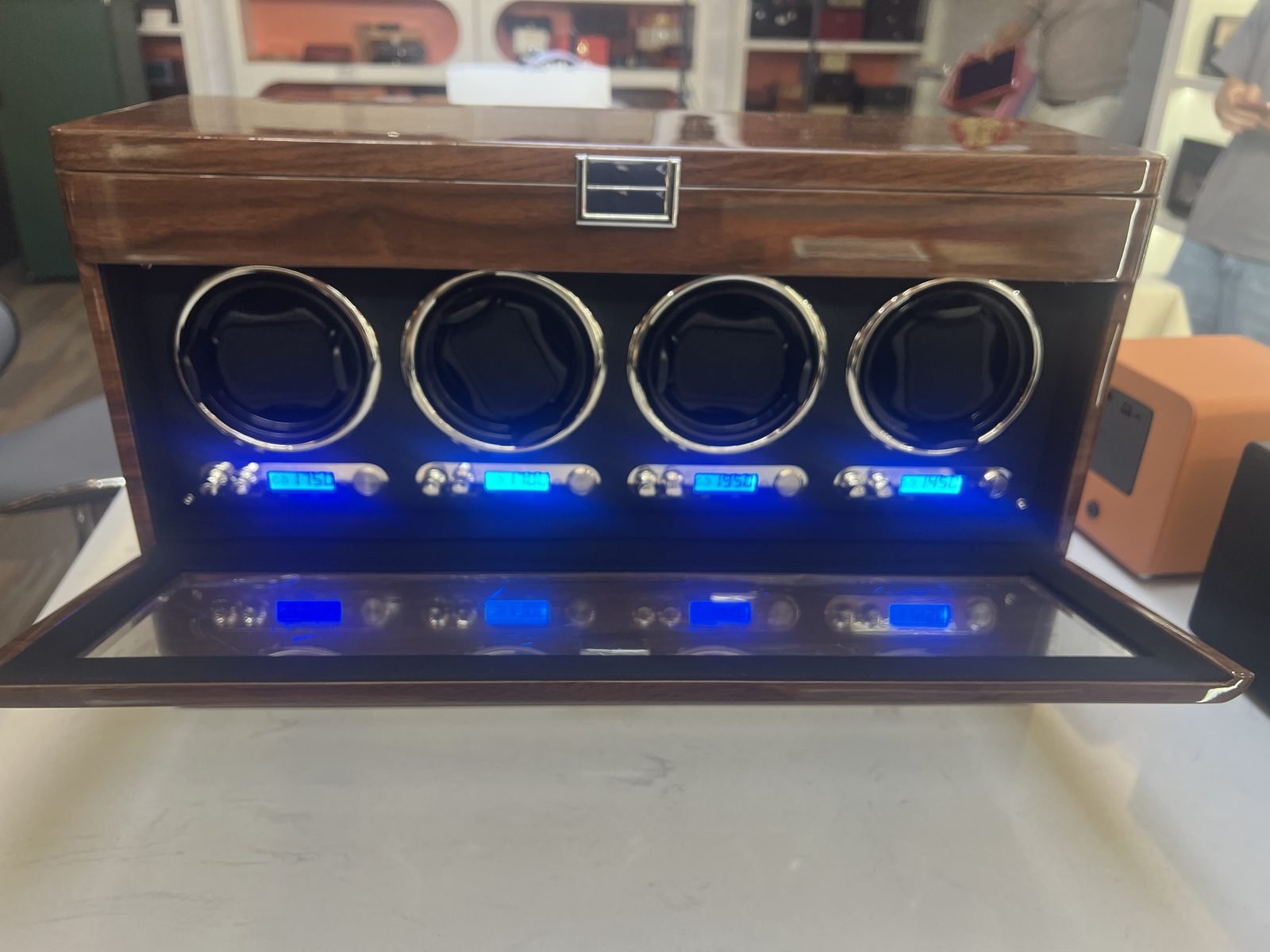 Four-slot watch winder with the glass door open, showing the rotors and per-slot control panel