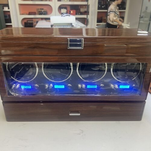 Four-slot walnut watch winder with glass door and blue LCD displays, front view