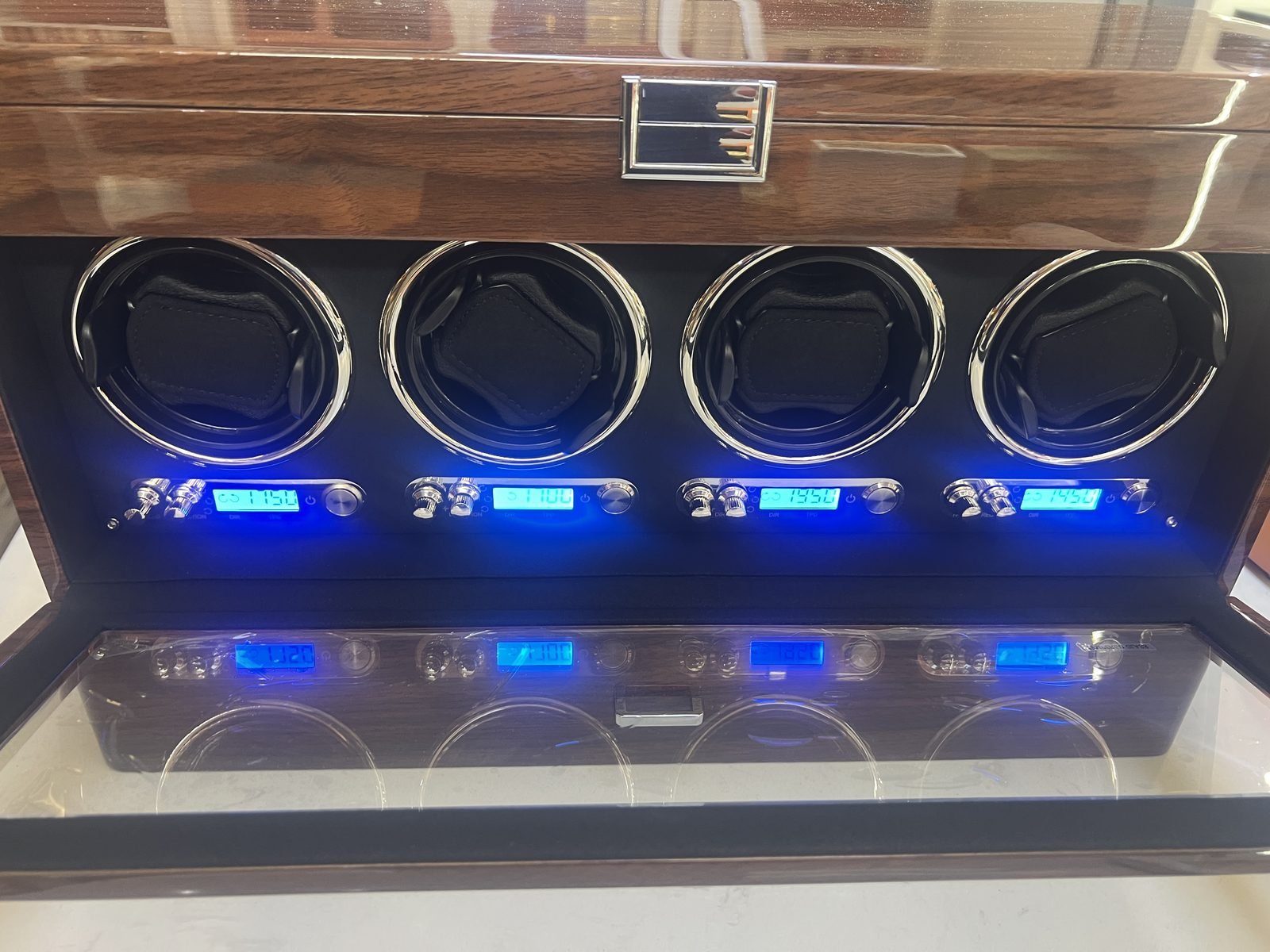 Interior of a four-slot watch winder with chrome rotor bezels, leather watch pillows and a walnut lid
